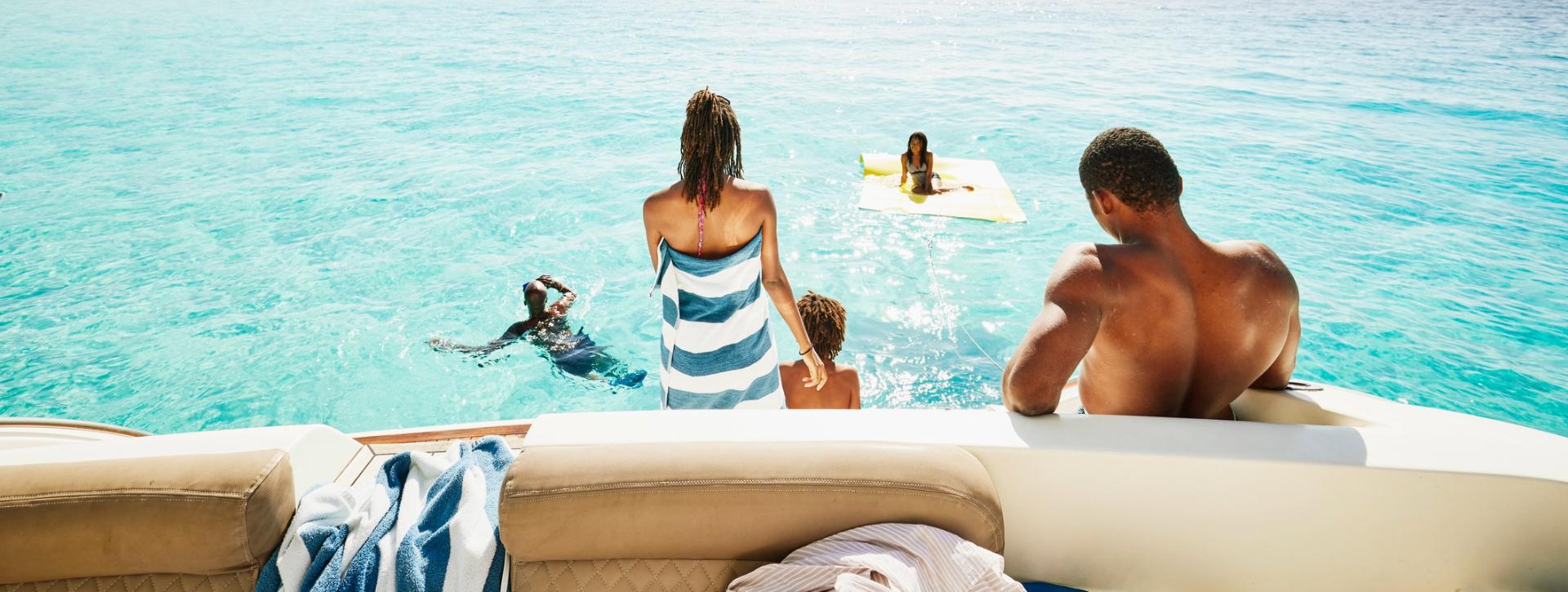 Family on a boat relaxing and swimming together in turquoise ocean water