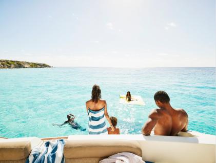 Family on a boat relaxing and swimming together in turquoise ocean water