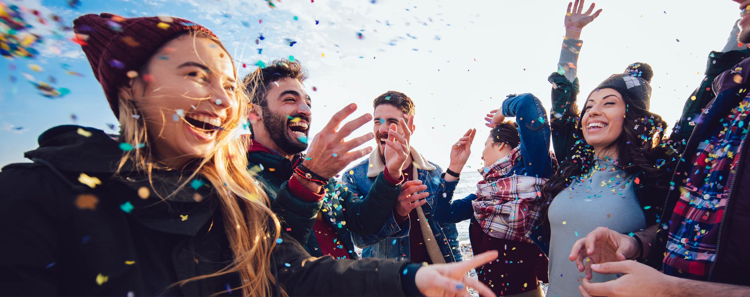 A group of people share celebratory smiles with confetti floating around them