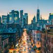 New York City skyline with a brightly lit bustling city street in foreground